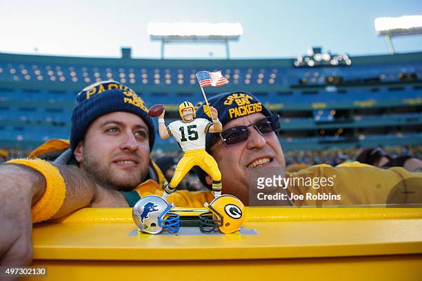 Two fans pose with their bobblehead during the NFL game between the Green Bay Packers and the Detroit Lions at Lambeau Field on November 15, 2015 in...
