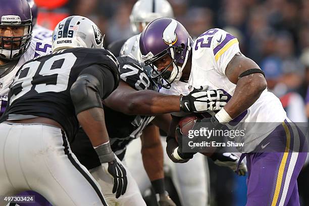 Running back Adrian Peterson of the Minnesota Vikings runs into the defense of defensive tackle Justin Ellis of the Oakland Raiders and outside...