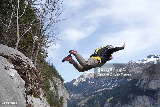 base jumper exited from a cliff. he must be crazy! - base jumping stock pictures, royalty-free photos & images