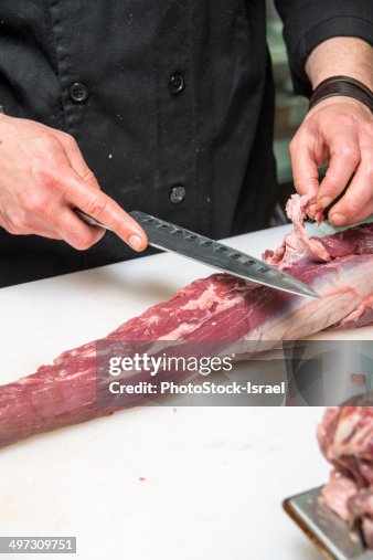 Chef removes fat from a beef cut Chef removes fat from a beef cut