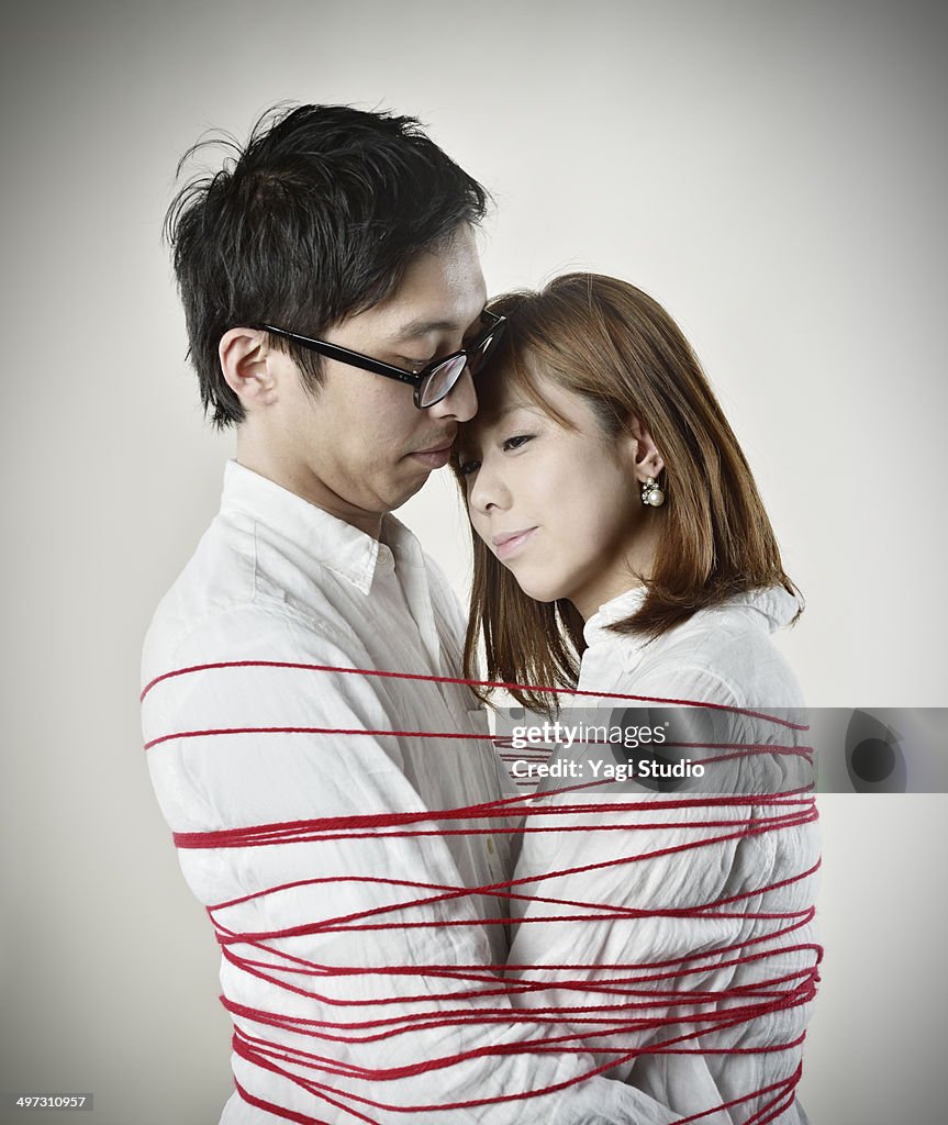 Couple hugging red thread is wound around