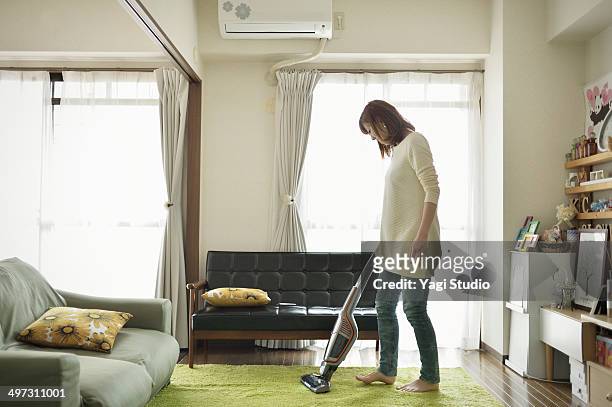 a woman cleans the room with a vacuum cleaner - vacuum cleaner woman stockfoto's en -beelden