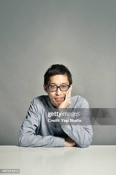 the man who rests his cheek on his hand on a table - hand on chin stock pictures, royalty-free photos & images