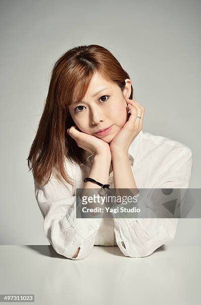 the woman who rests her cheek on her hand on table - woman hands on chin stock pictures, royalty-free photos & images