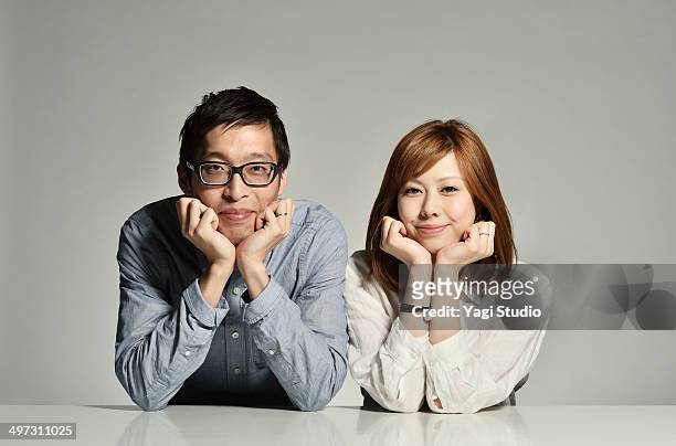 couple who rests its cheek on its hand on a table - woman hands on chin stock pictures, royalty-free photos & images