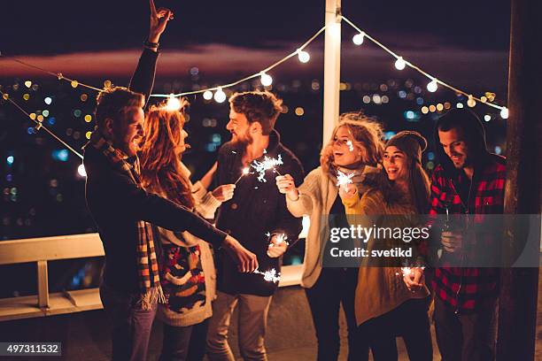 group of friends at rooftop party - friends with sparkler fireworks stock pictures, royalty-free photos & images