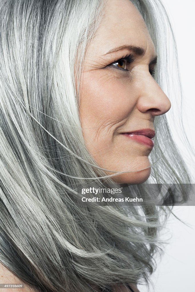 Grey haired woman with a soft smile, profile.