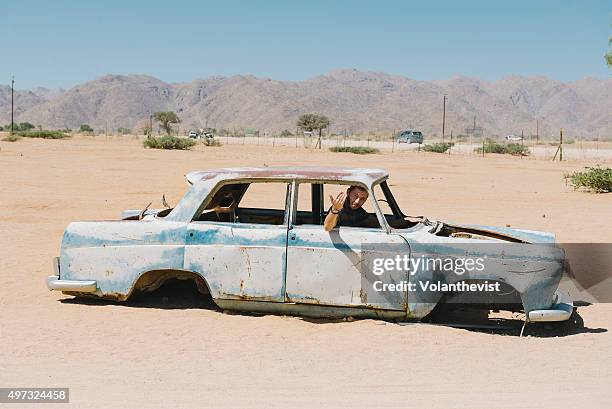 man driving a car abandoned on the namib desert, solitaire, namibia - restos de un accidente fotografías e imágenes de stock