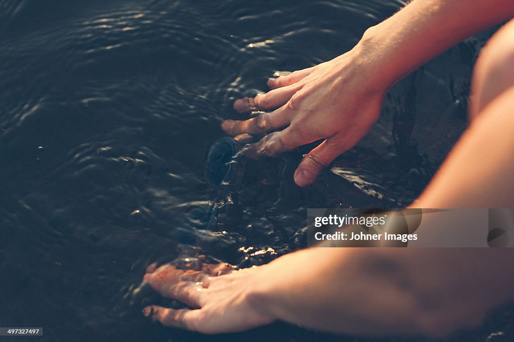 Hands washing diving goggles in water, Sweden