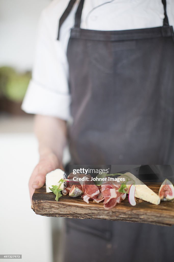 Man holding food on cutting board, close-up