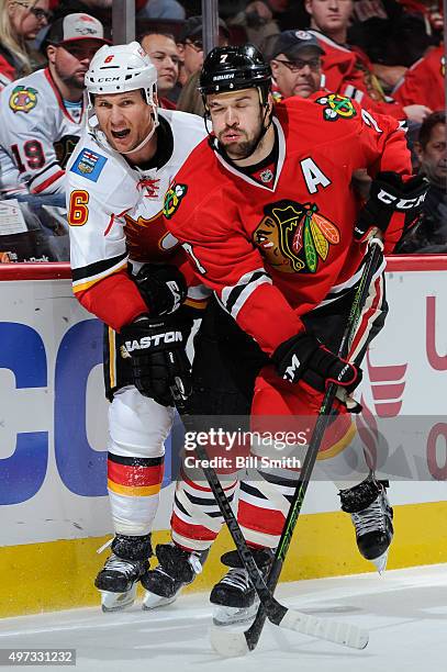 Dennis Wideman of the Calgary Flames and Brent Seabrook of the Chicago Blackhawks skate around the boards in the third period of the NHL game at the...