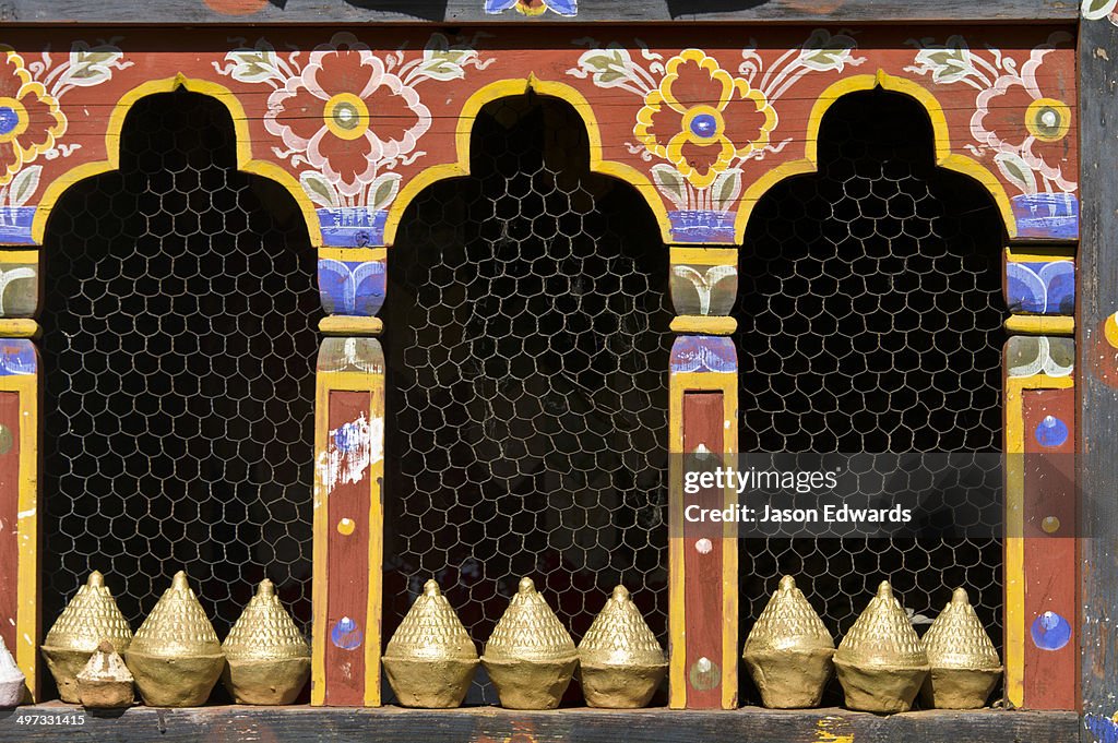 A row of mini tsa tsa stupas line the sill of a decorative window in a temple.