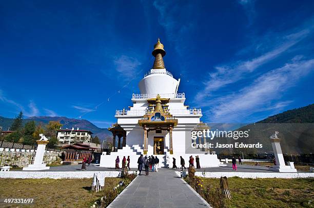 pilgrims circle the memorial chorten with it's golden spire and bells offering prayers. - bhutan imagens e fotografias de stock