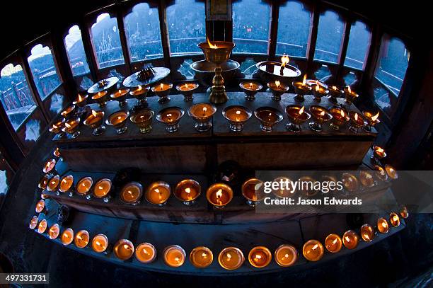 tiered steps in a himalayan buddhist monastery lined with rows of butter lamps for prayers and worship. - bhutan stock pictures, royalty-free photos & images