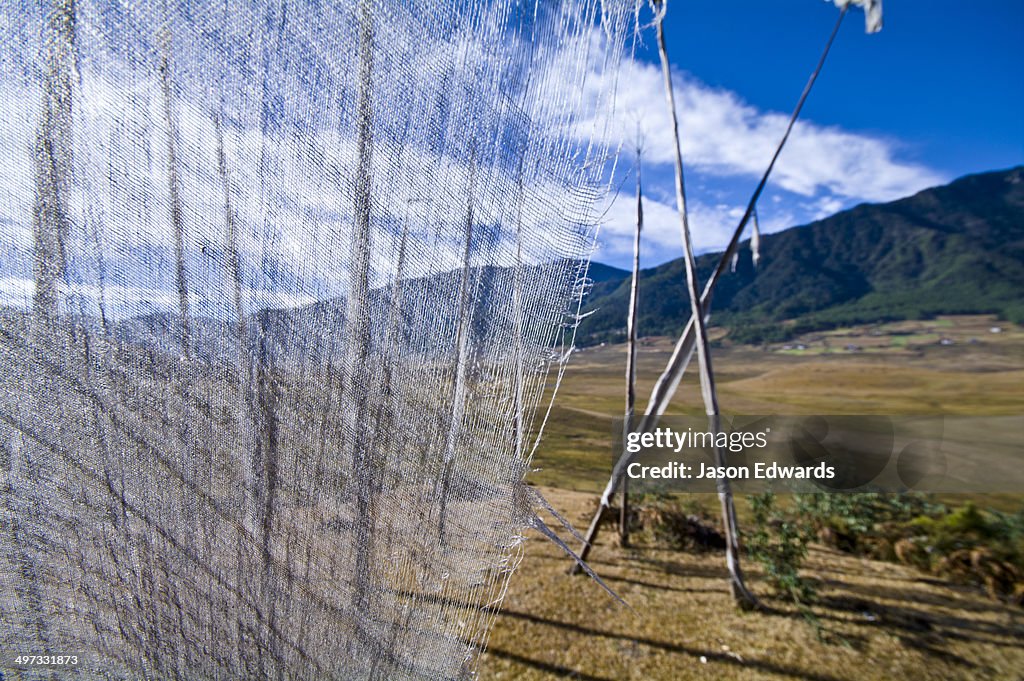 The translucent cloth of a prayer flag fluttering in the wind above a Himalaya wetland.