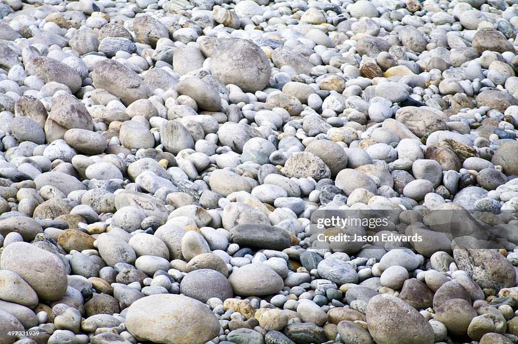 A pebble and boulder strewn riverbank in a Himalaya valley.