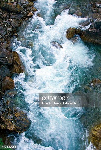 icy water from snowmelt rushes through a mountain gorge between boulders in the himalaya. - wildwasser fluss stock-fotos und bilder