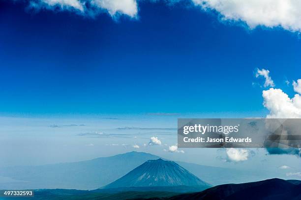 clouds circle the summit of primeval volcano caldera shrouded in forests above the savannah plain. - aerial top view steppe stock pictures, royalty-free photos & images