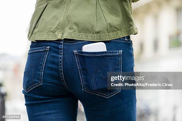 woman carrying smartphone in back pocket - woman jeans stock pictures, royalty-free photos & images