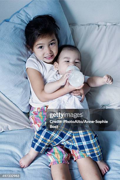 little girl feeding baby brother - brother sister stock pictures, royalty-free photos & images