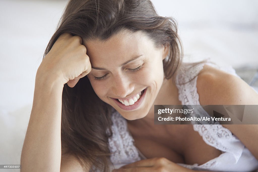 Young woman leaning on elbow, looking down, portrait