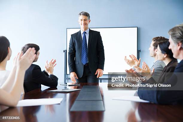 business associates applauding colleague at meeting - applauding leader stock pictures, royalty-free photos & images