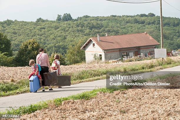 mother and children wandering through countryside, dragging suitcases behind them - homeless family stock pictures, royalty-free photos & images