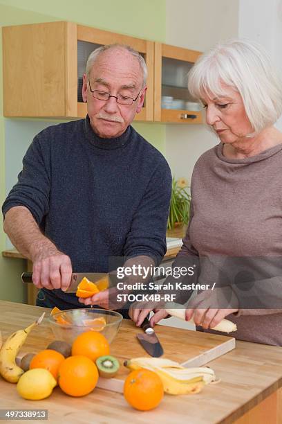 senior couple preparing fruit salad in kitchen - fruit salad stock pictures, royalty-free photos & images