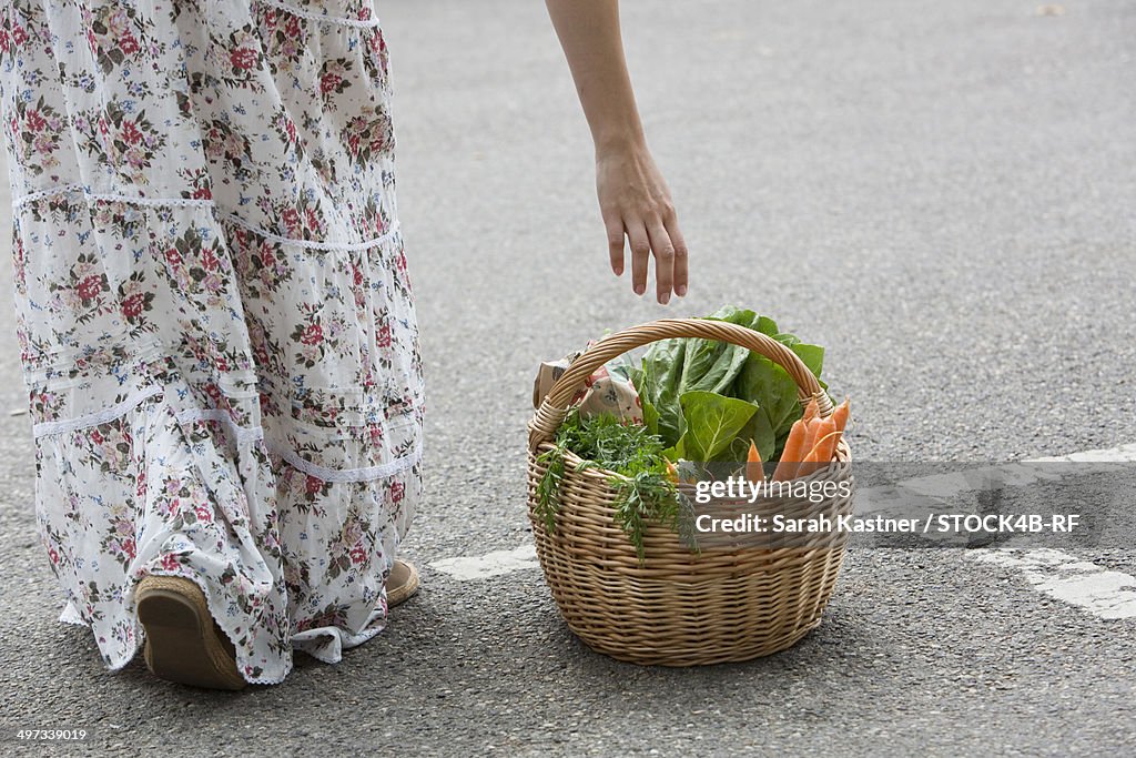 Woman reaching for basket full of fresh vegetables
