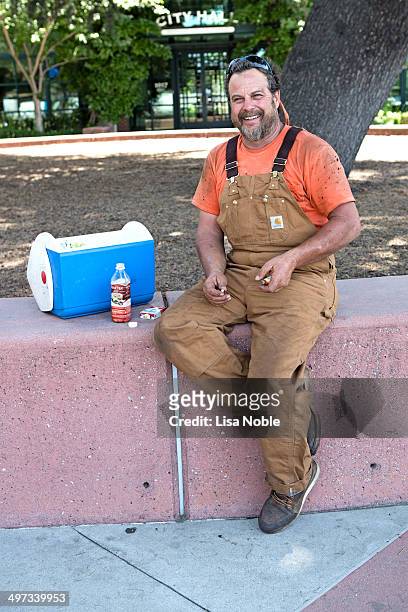 Construction worker with a beard, coveralls and lunch box on lunch break in redwood city California USA