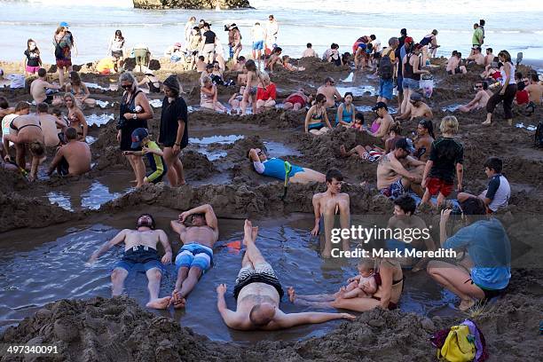 Crowd gathers at low tide at Hot Water Beach in the Coromandel to sit in hot pools created by geothermal activity beneath