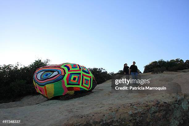 Two women walk near a yarn bomb at Lizard's Mouth, Santa Barbara, California.