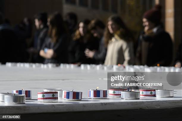 Students stand behind candles with colours of French and Lebanese national flags during a gathering on November 16, 2015 at the Swiss Federal...