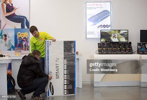 An employee talks to a customer as he wraps a boxed Smart TV television, manufactured by Samsung Electronics Co., inside an order fulfillment centre,...