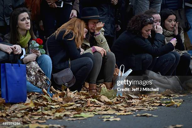 Members of the public grieve as they sit opposite the main entrance of Bataclan concert hall as French police lift the cordon following Fridays...