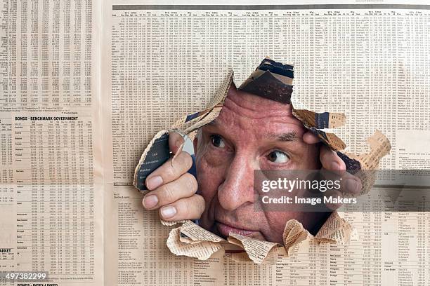 man peers through hole in financial paper - ripped newspaper stock pictures, royalty-free photos & images