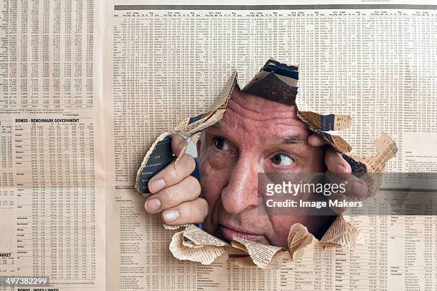 man peers through hole in financial paper - paper england imagens e fotografias de stock