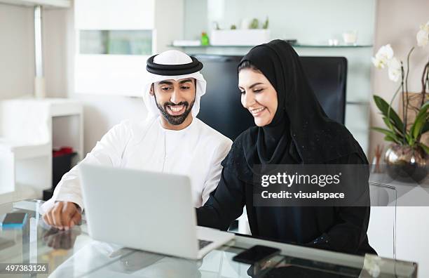 arab couple discussing business at home using laptop - emirati laptop stock pictures, royalty-free photos & images