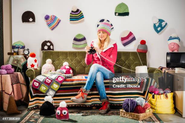 young woman knitter portrait on couch with winter hats - knitting - fotografias e filmes do acervo