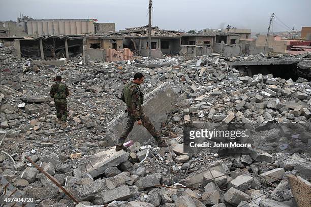 Kurdish Peshmerga soldiers searches for weapons in the rubble of an airstrike on November 16, 2015 in Sinjar, Iraq. Kurdish forces, with the aid of...