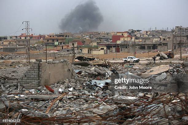 Smoke rises in the distance, on a day when ISIL fighters fired multiple Katyusha rockets at Kurdish Peshmerga forces occupying the ruins of the town...