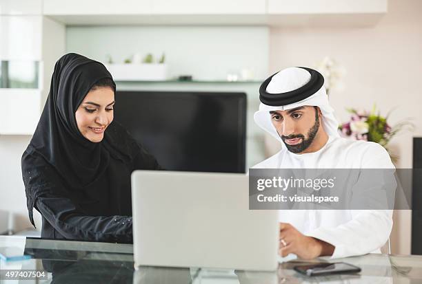 muslim man buying online for his wife - emirati laptop stock pictures, royalty-free photos & images