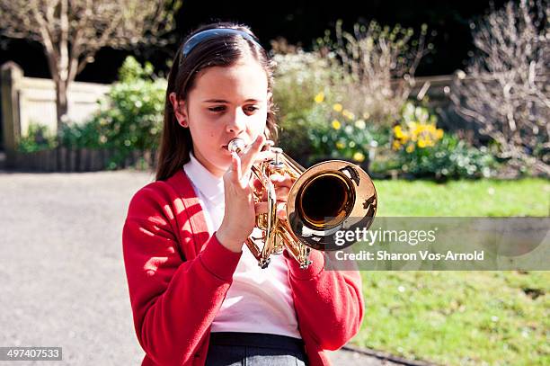 girl playing trumpet, school uniform, garden - trompet stockfoto's en -beelden