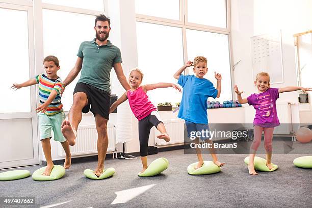 happy children doing balance exercises with their coach. - balancing child stock pictures, royalty-free photos & images