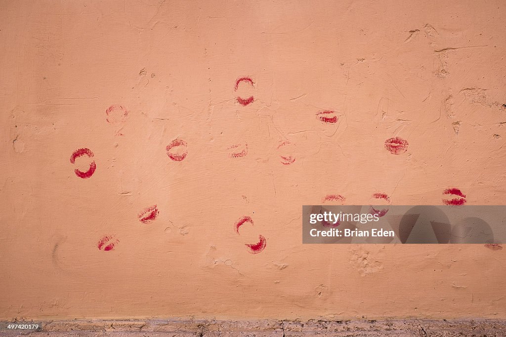 Lipstick kisses on a peach wall in Trastevere Rome