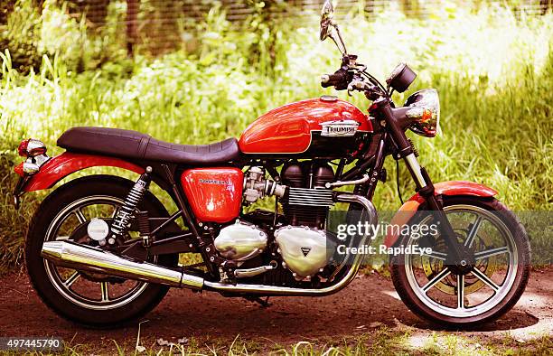 retro-style 2012 triumph bonneville motorbike next to tall grass - triumph motorcycle bildbanksfoton och bilder