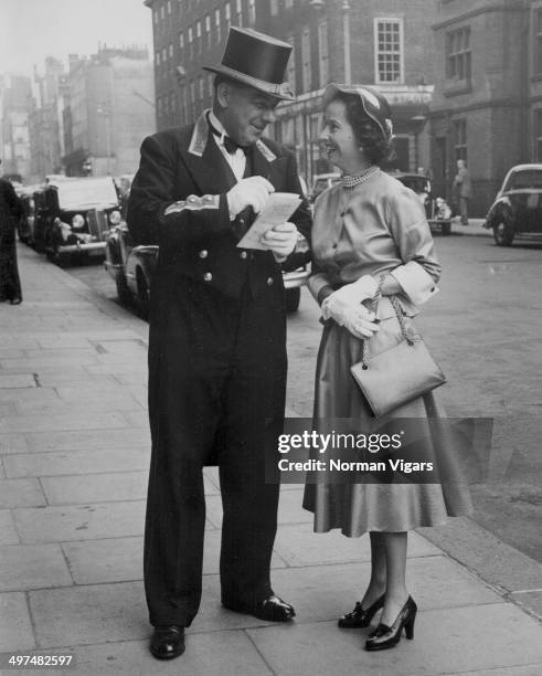 Actress Merle Oberon getting a tip from Commissionaire Warburton of Claridge's Hotel, as she leaves for Royal Ascot, London, June 13th 1950.