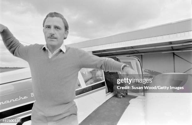 British racecar driver and team owner Graham Hill hops off the wing of a private plane at an unidentfied airfield, England, January 1970.