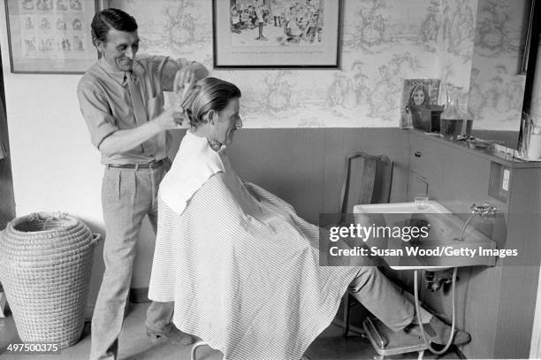 British racecar driver and team owner Graham Hill sits in a barber's chair, London, England, January 1970.