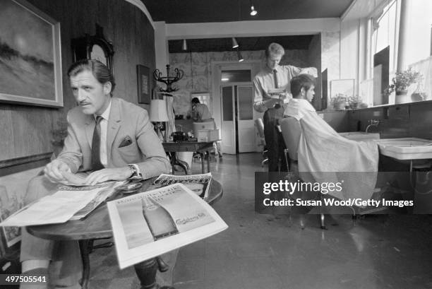 British racecar driver and team owner Graham Hill waits his turn in a barber's shop, London, England, January 1970.